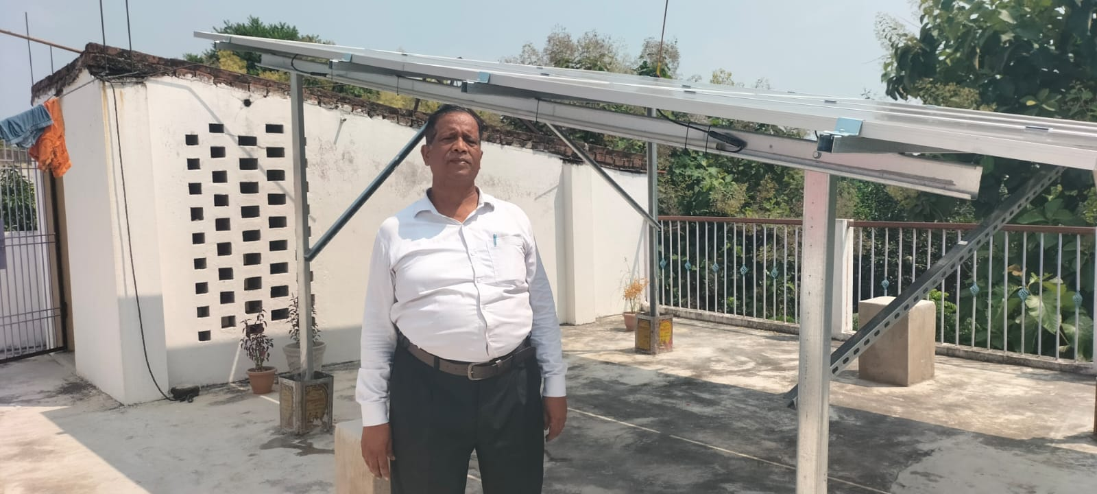 Harendra Kumar Gupta standing beneath a solar mounting structure on a rooftop.
